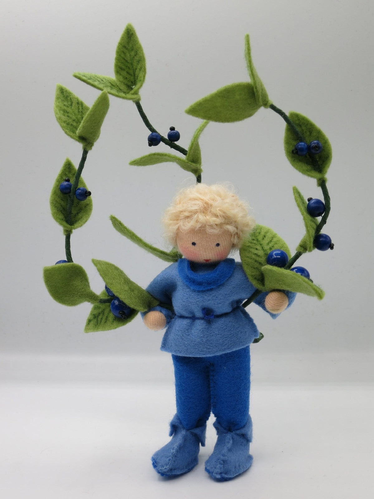 Heidelbeere-Junge mit Beerenbogen, blauem Oberteil und Filzstiefeln, Gesamtansicht.
