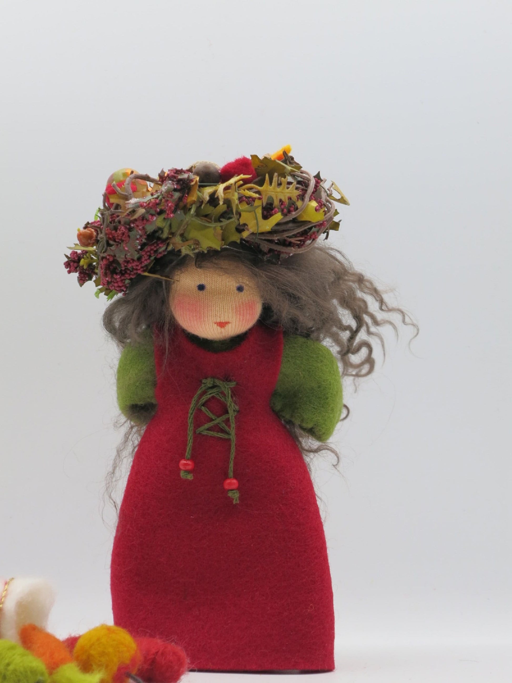 Handgefertigte Herbstfigur im roten Filzkleid mit grauem Wollhaar und üppigem Kranz aus Blättern, Beeren und Naturmaterialien