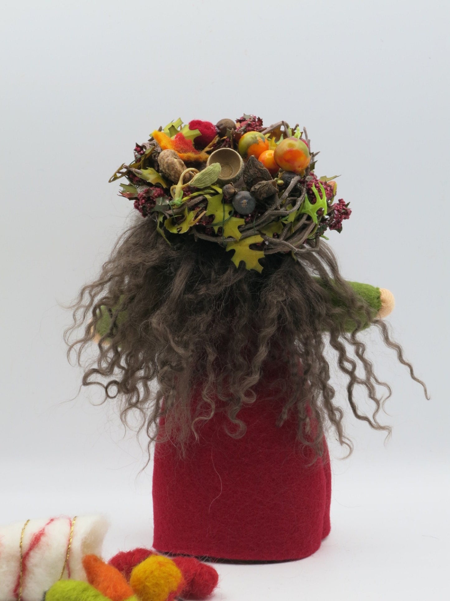 Rückansicht der Herbstfigur mit grauem Wollhaar und Erntedank-Kranz aus Eicheln, Beeren, Früchten und Blättern