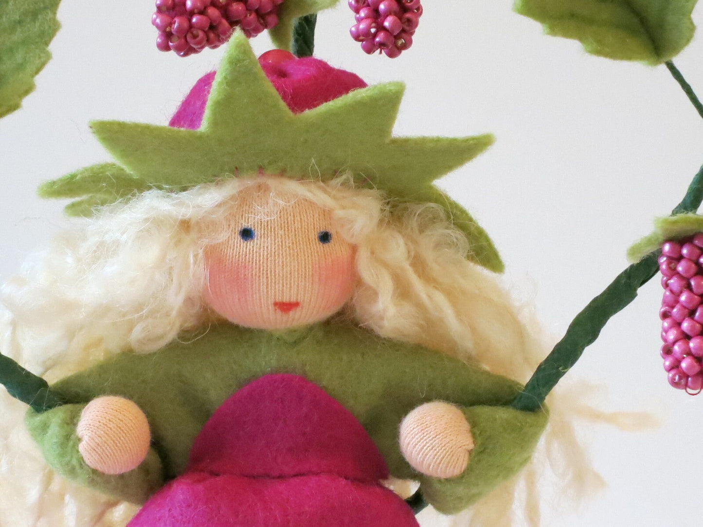 Nahaufnahme des Gesichts vom Himbeere-Blumenkind mit himbeerförmiger pinker Haube
