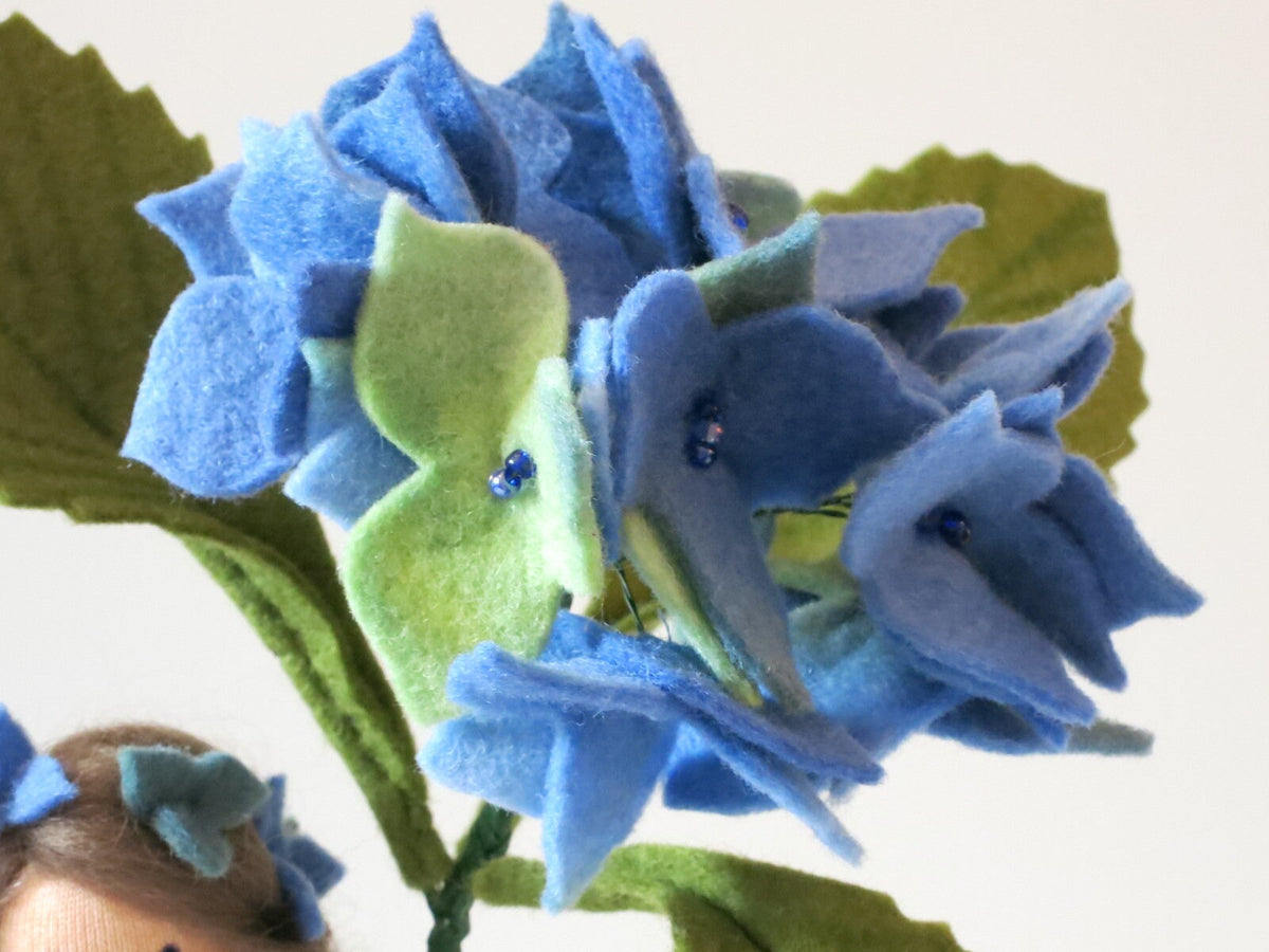 Detailaufnahme der blauen Hortensien-Blüten mit kleinen Glasperlen in der Blattmitte.