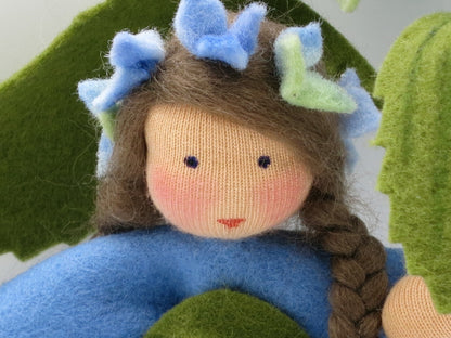 Nahaufnahme des Gesichts der blauen Hortensien-Figur mit Blütenkranz im braunen Zopf.