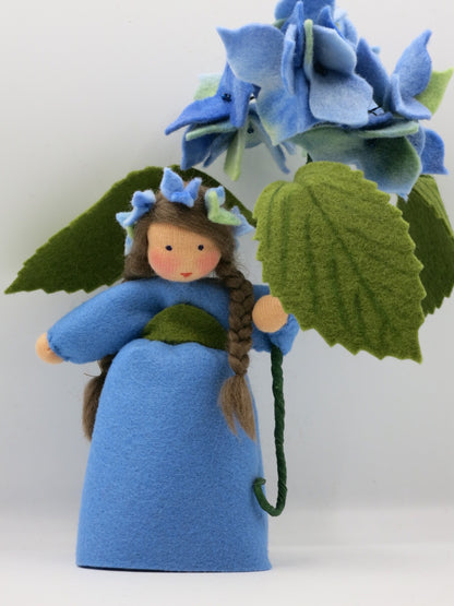 Rückansicht der blauen Hortensie mit großem grünem Blatt und Blütenkranz im Haar.