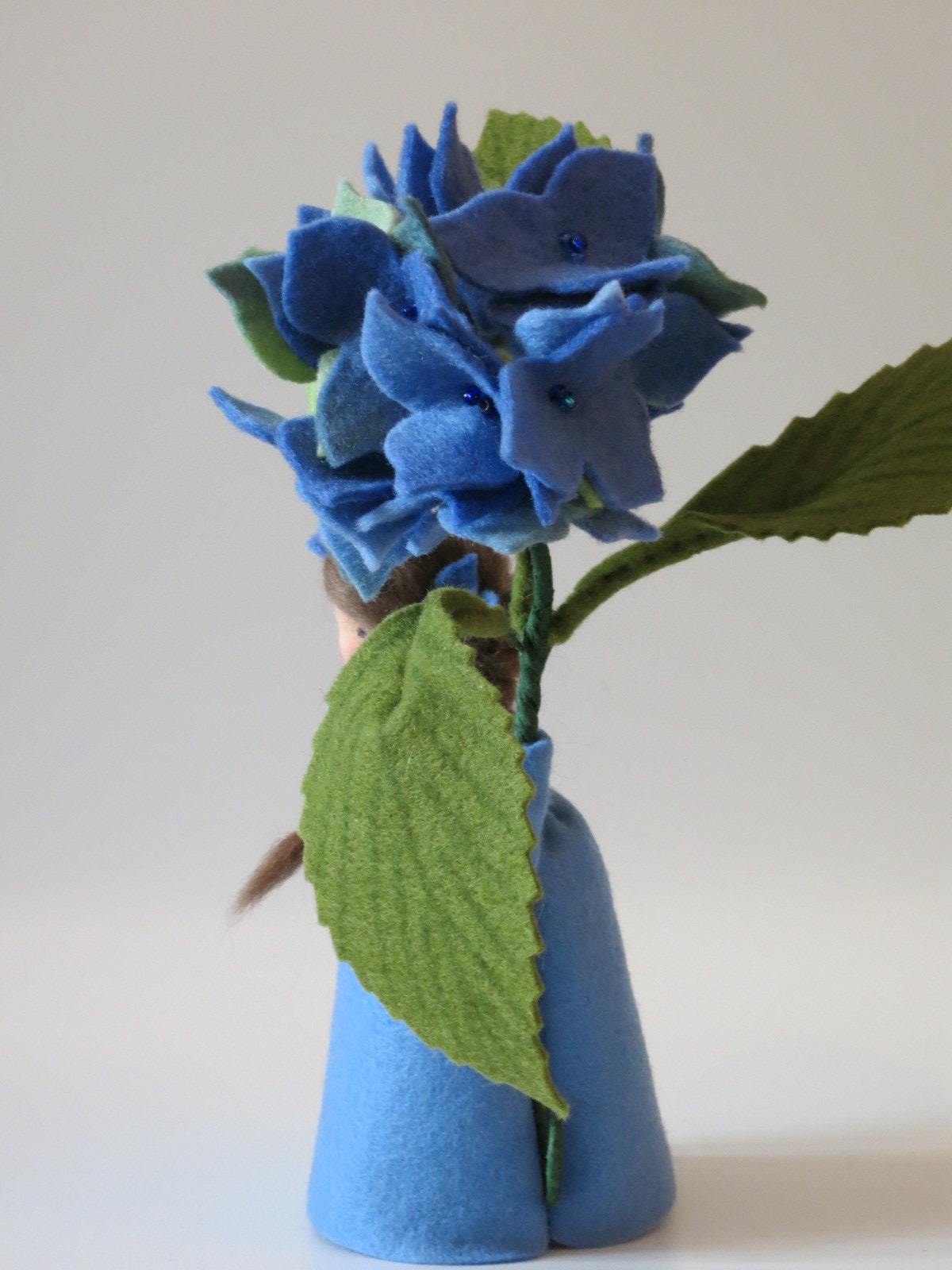 Rückansicht der blauen Hortensie mit geflochtenem Zopf und großem gezähntem Blatt.