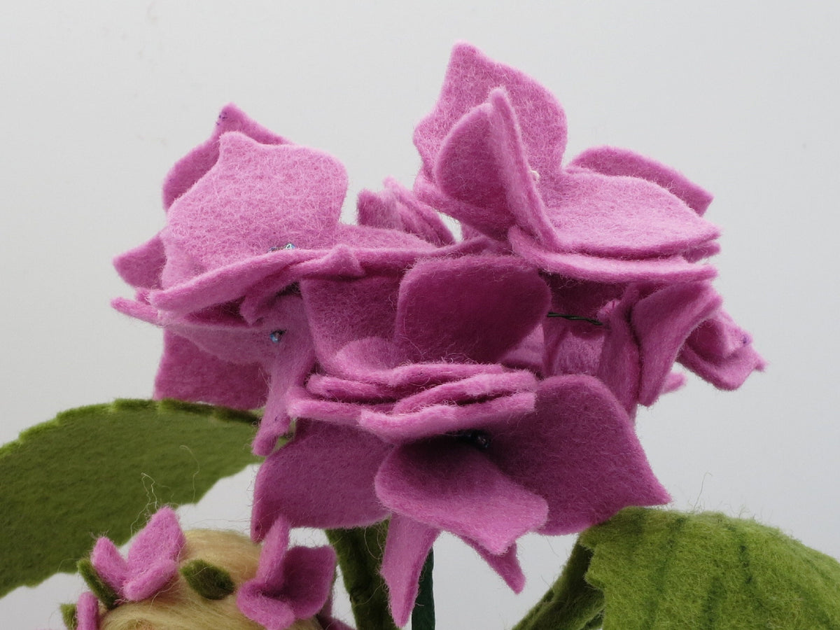 Rückansicht des lila Hortensie-Blumenkindes mit blondem Zopf und Blütenkranz.