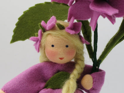 Nahaufnahme des Gesichts der rosa Hortensien-Figur mit Blütenkranz im blonden Zopf.