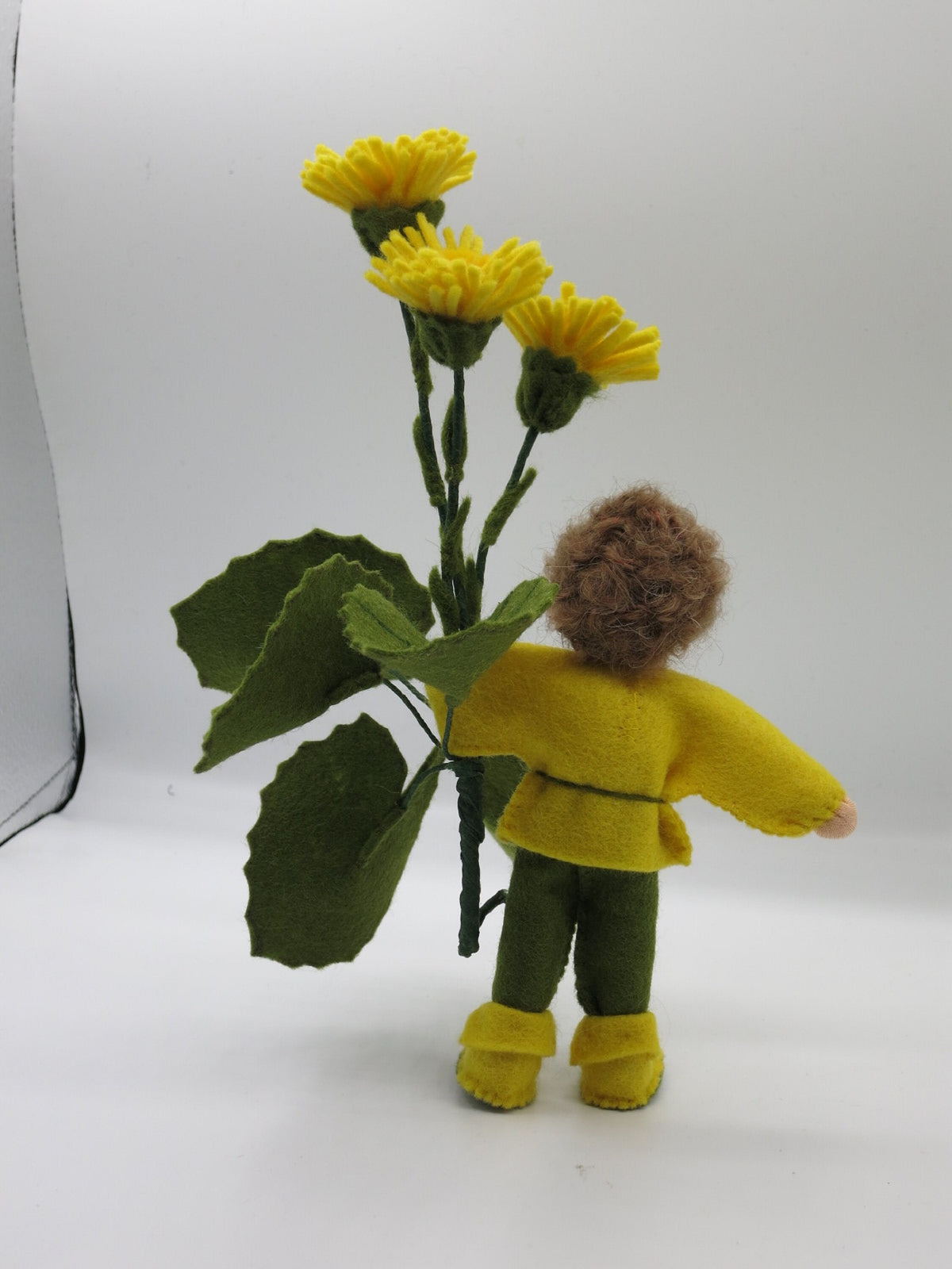 Rückansicht des Huflattich-Junge Waldorf Jahreszeitentisch Blumenkindes mit großen Filzblättern