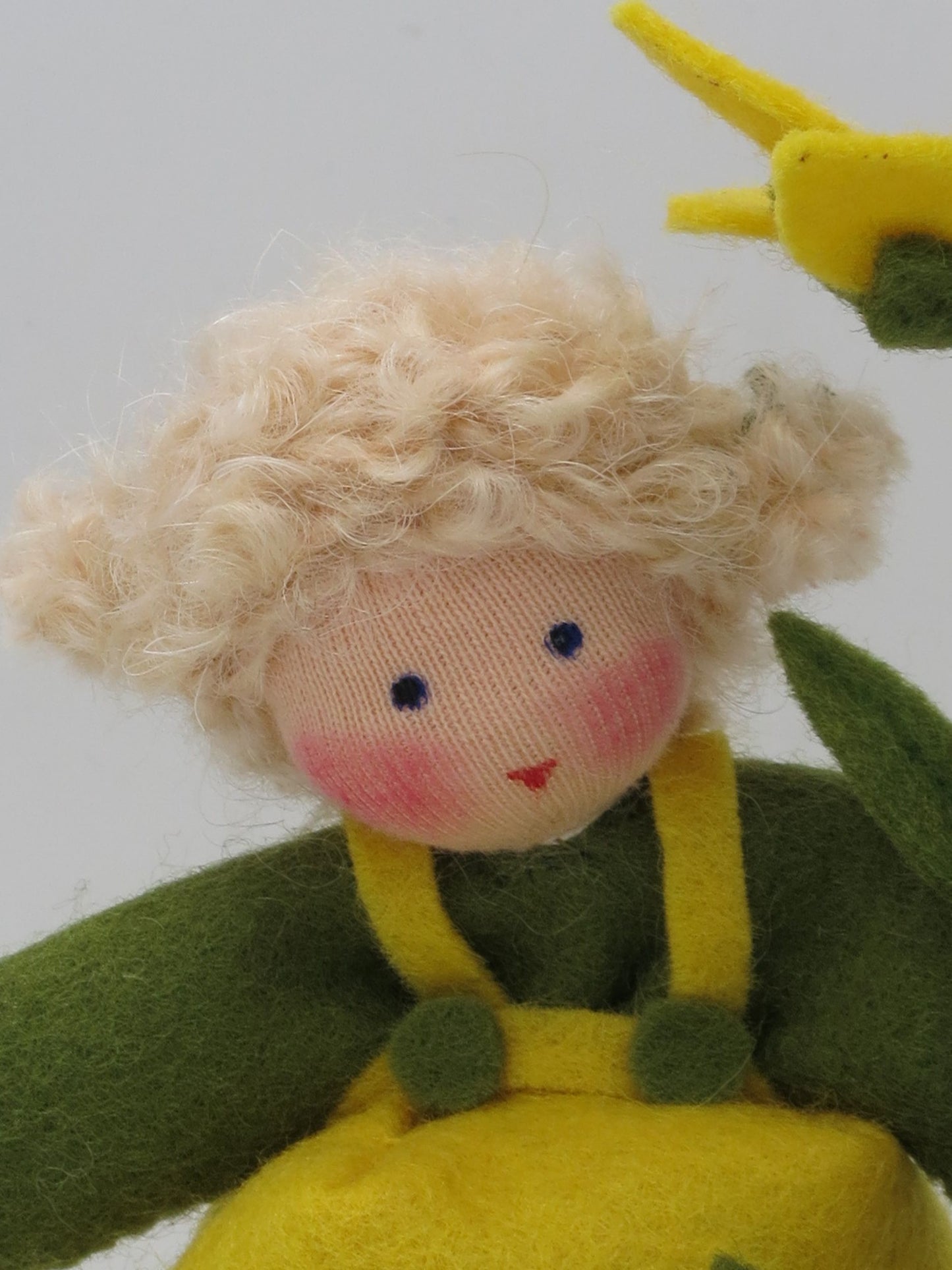 Nahaufnahme des Gesichts vom Johanniskraut-Mädchen mit gelber Blüte im Hintergrund.