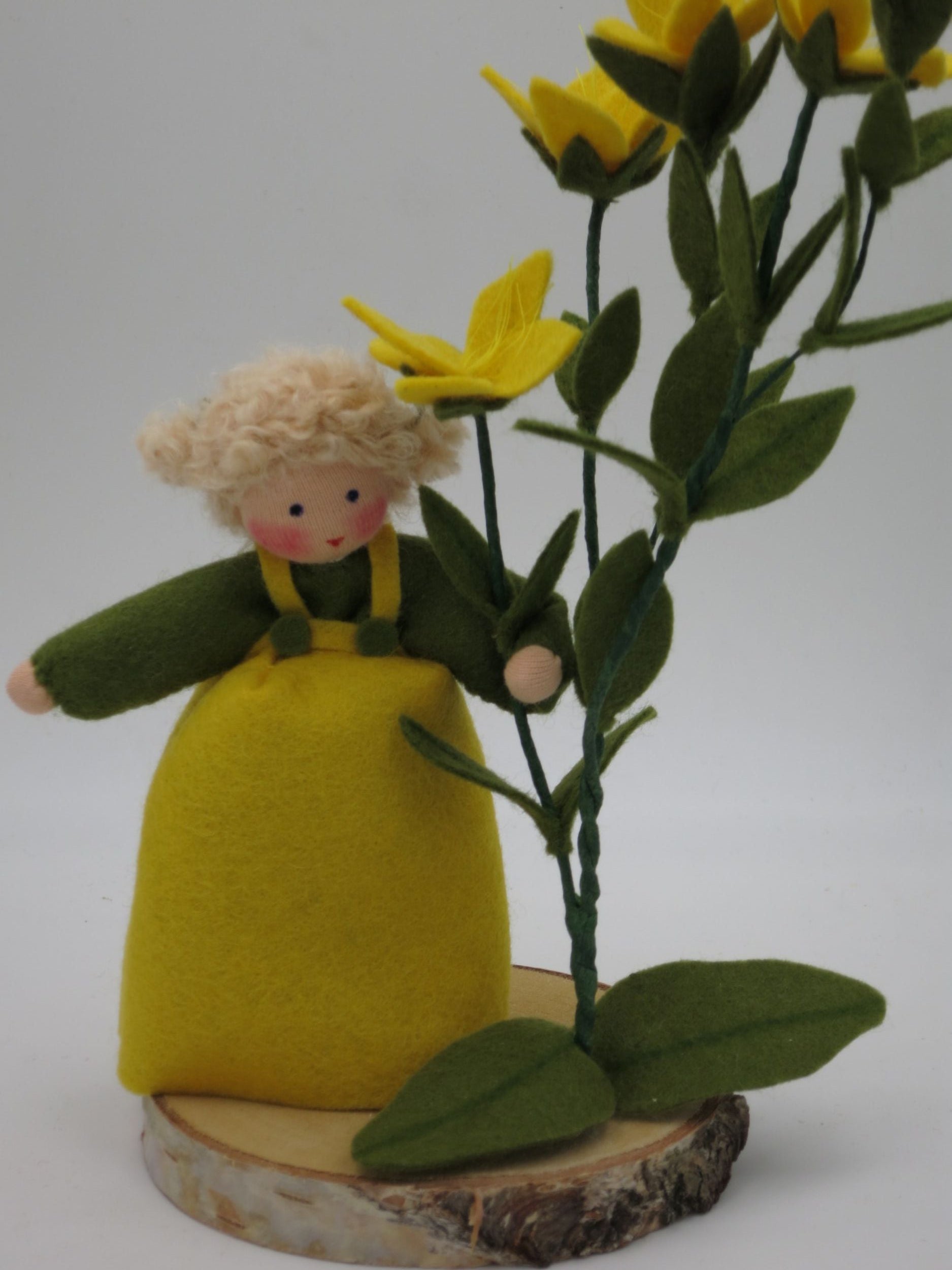 Rückansicht des Johanniskraut-Mädchens mit gelben Filzblüten und grünem Blattwerk.