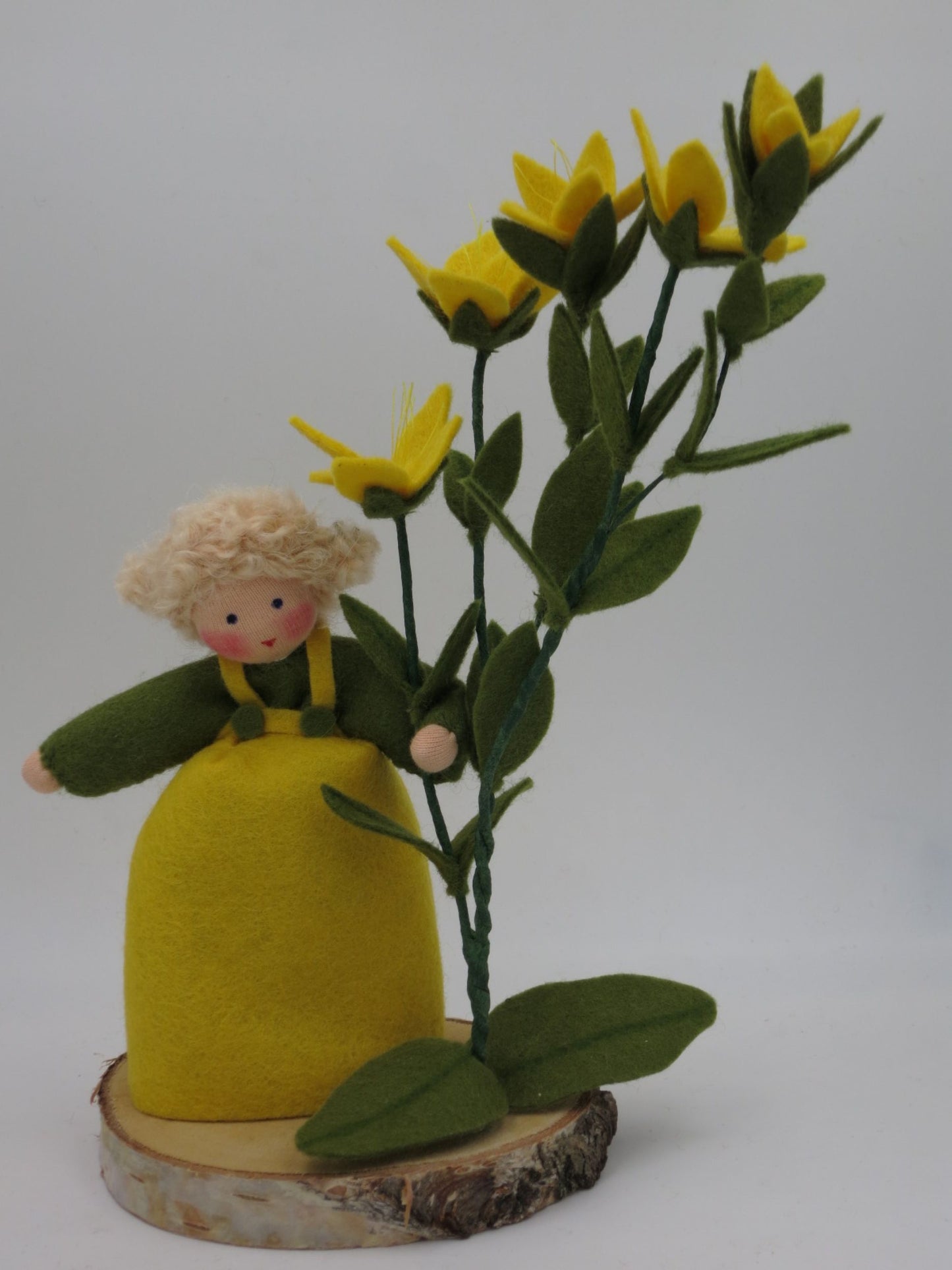 Johanniskraut-Mädchen als Blumenkind aus Wollfilz für den Waldorf Jahreszeitentisch mit fünf gelben Sternblüten auf Birkenholzscheibe.