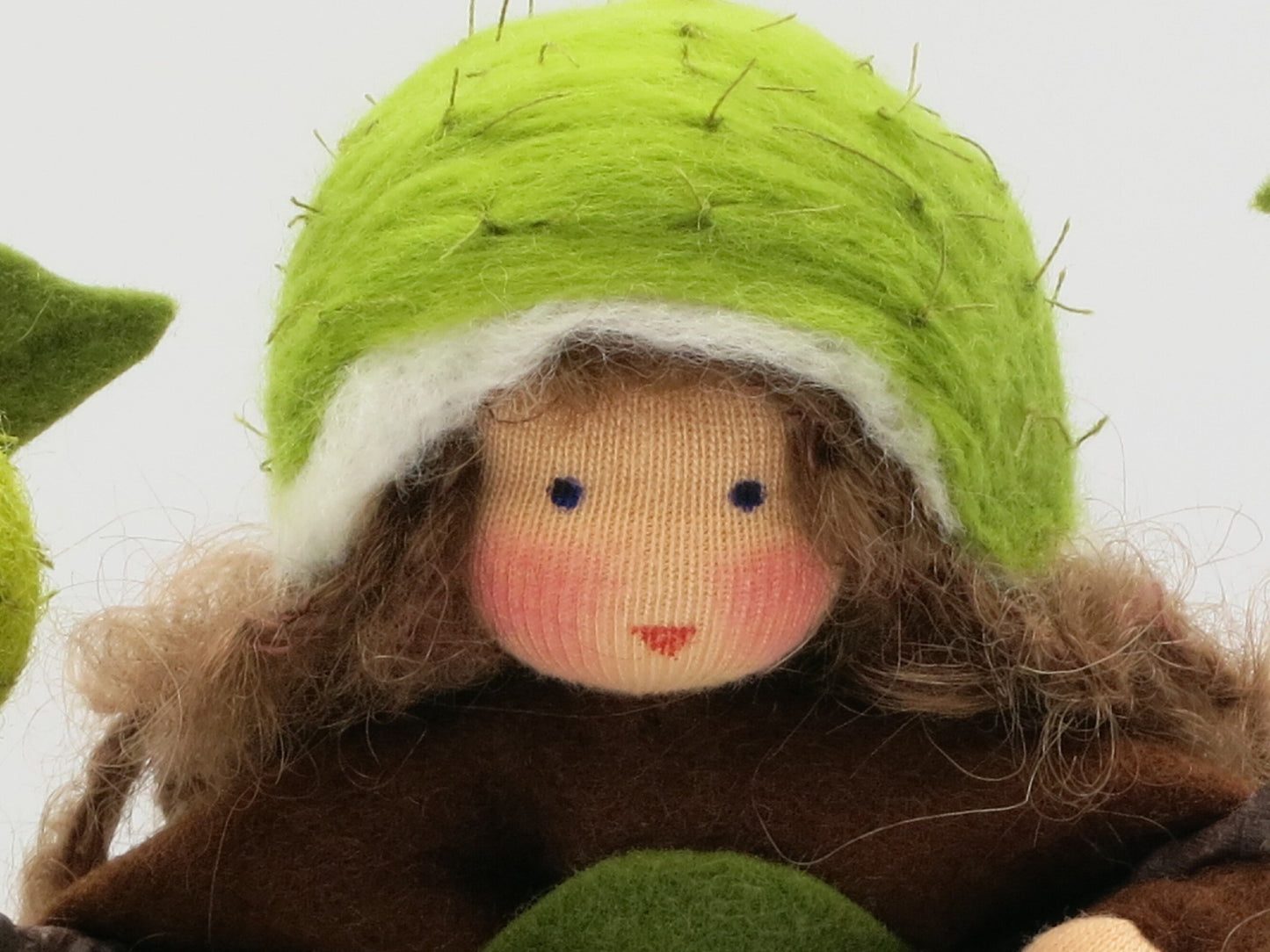 Kastanie Blumenkind aus Wollfilz, Nahaufnahme Gesicht mit stacheliger Kastanienhuelle als Haube, Waldorf-Jahreszeitentisch, Art. HE6