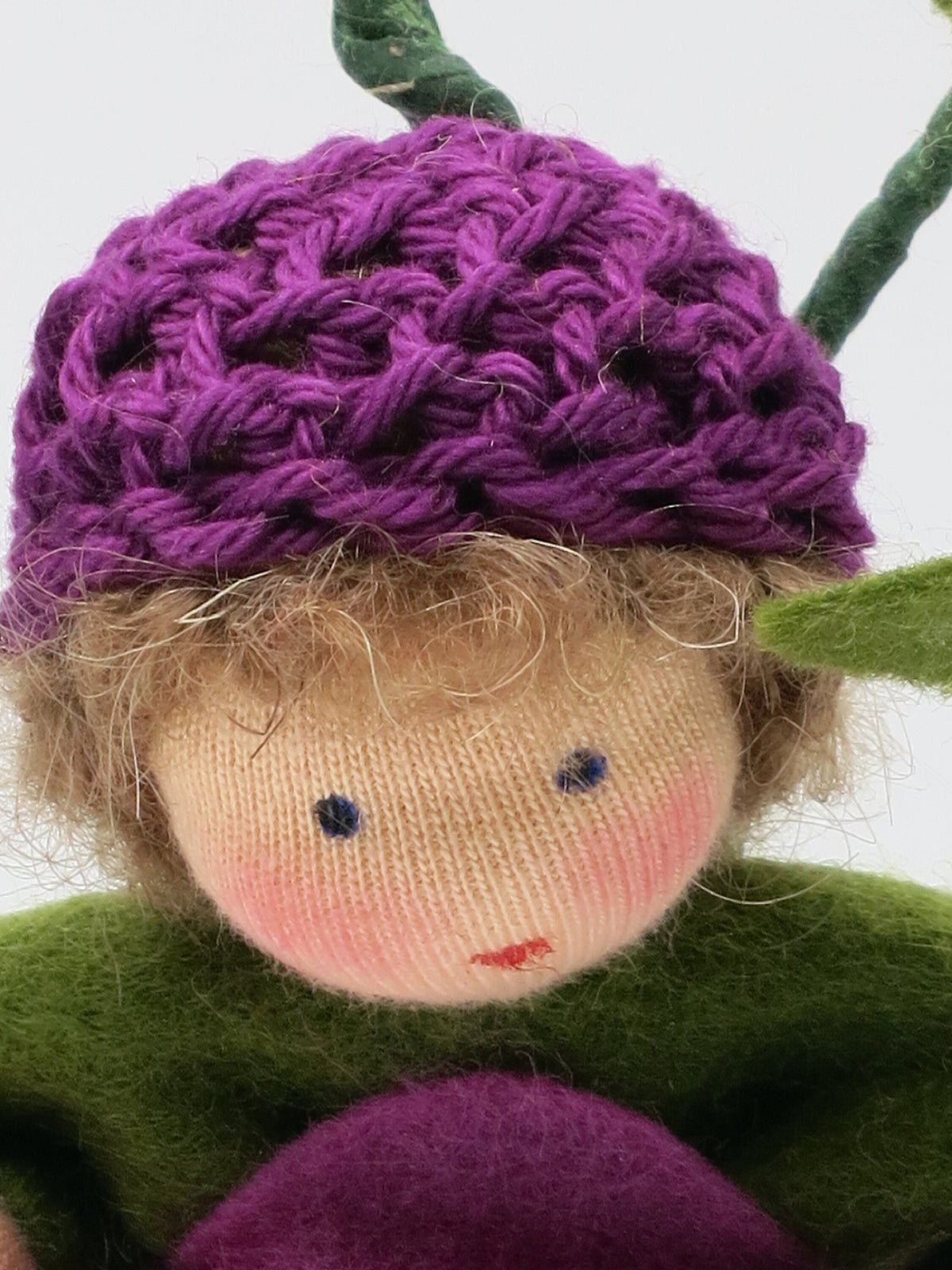 Nahaufnahme des Gesichts der Klee-Figur unter der violetten Häkelmütze.