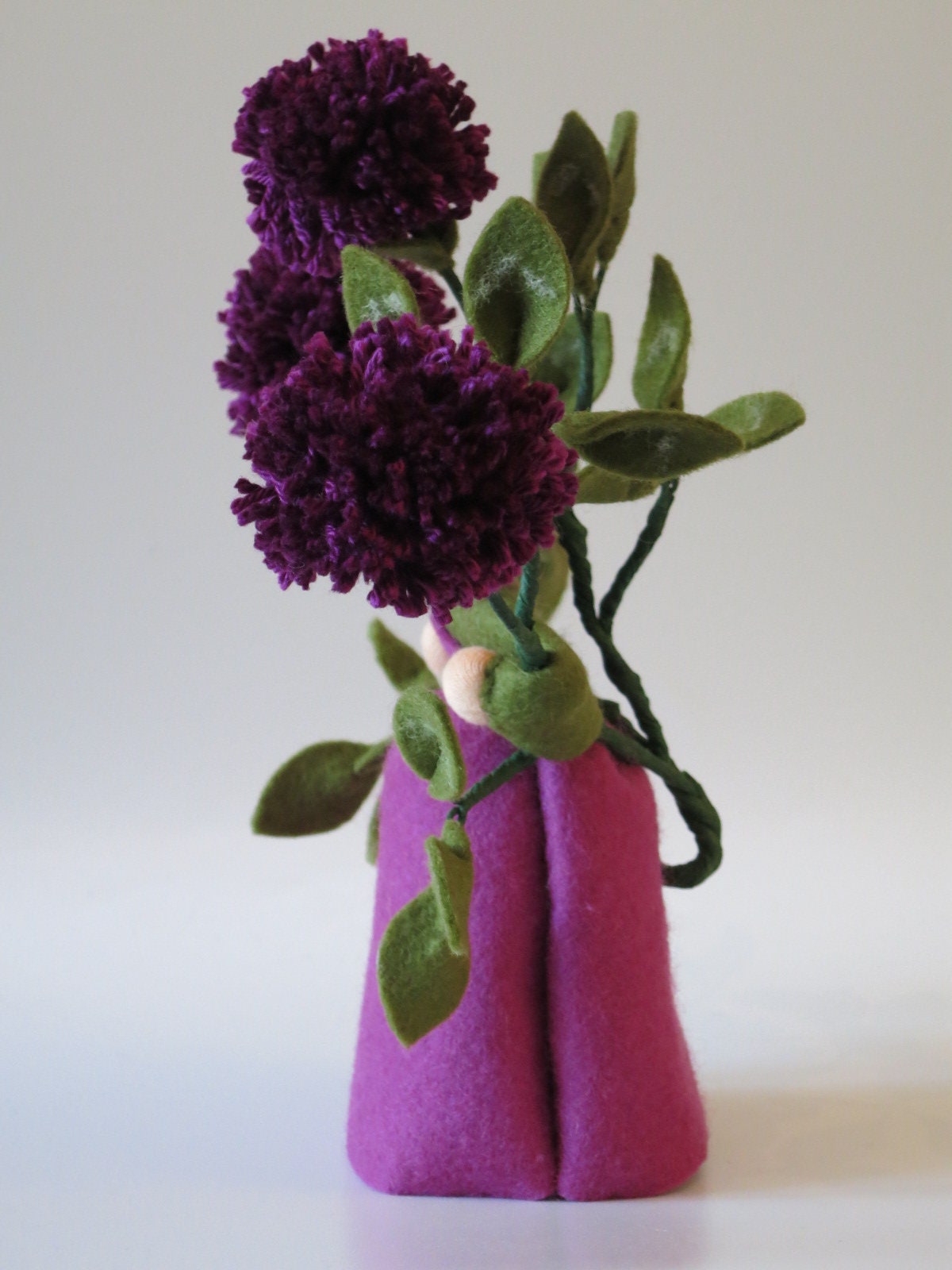 Rückansicht des Klee-Blumenkindes mit vier Blütenzweigen und Häkelmütze.