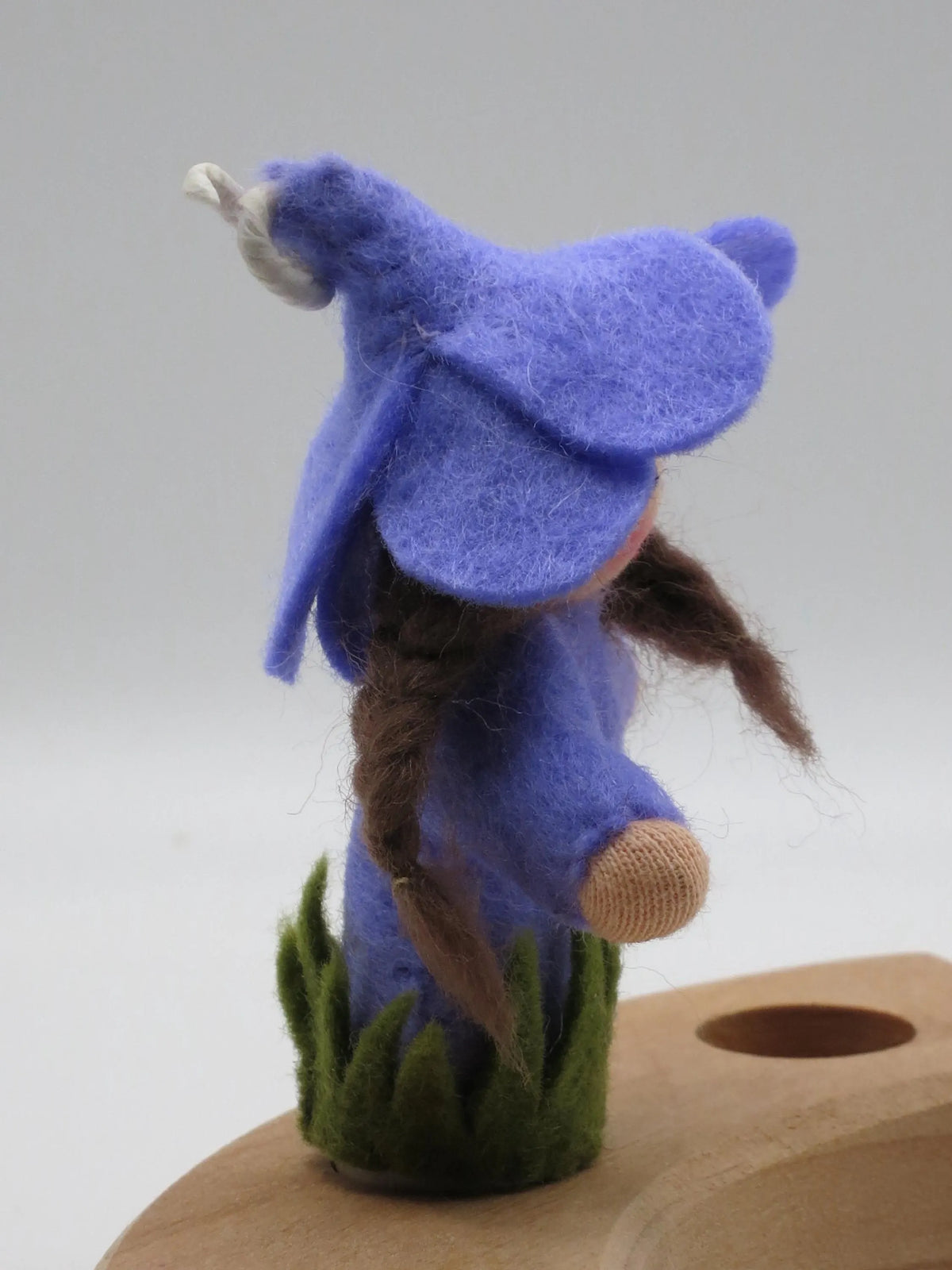 Rückansicht des Krokus-Steckers mit langem braunem Zopf und blauer Filzblütenhaube