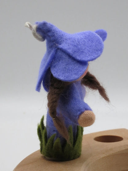 Rückansicht des Krokus-Steckers mit langem braunem Zopf und blauer Filzblütenhaube