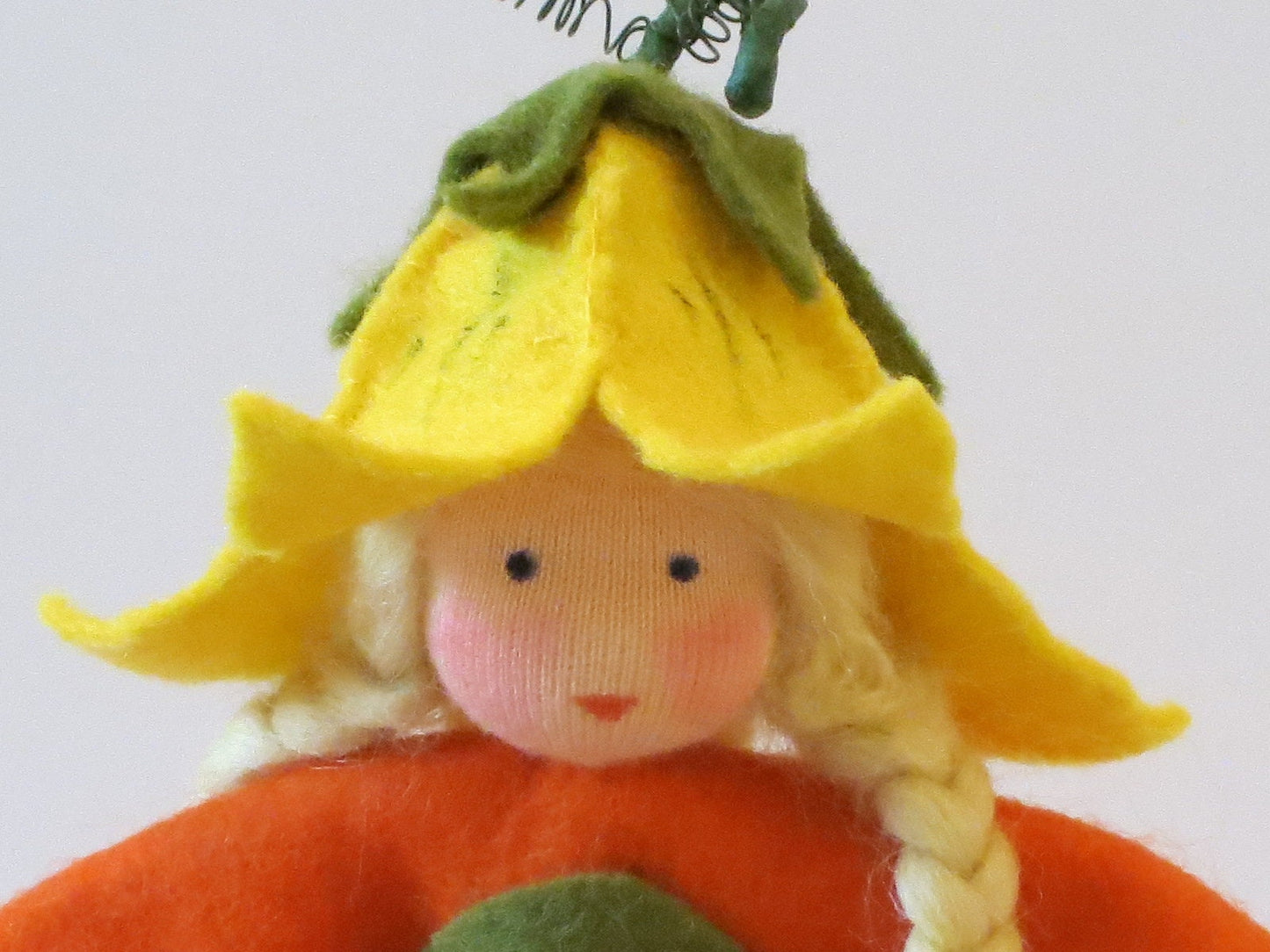 Nahaufnahme der gelben Kürbisblüten-Haube am Kürbis-Mädchen Art. HE51, Waldorf-Jahreszeitentisch Herbst.