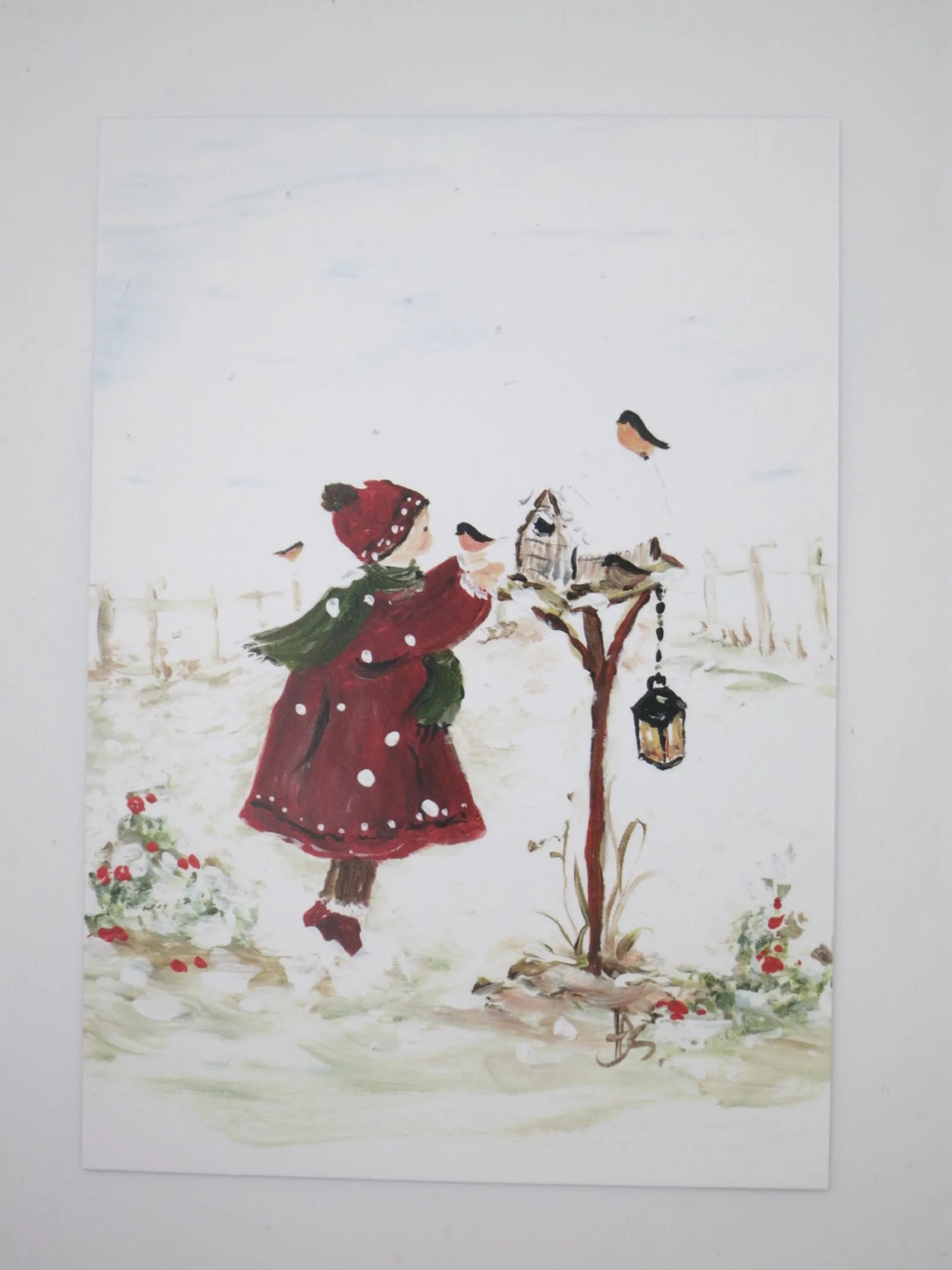 Kunst-Postkarte „Schneeflocke und Freunde“ von Hildegard Seeger: Mädchen füttert Gimpel am Futterhaus im Schnee, Postkarte mit Motiven