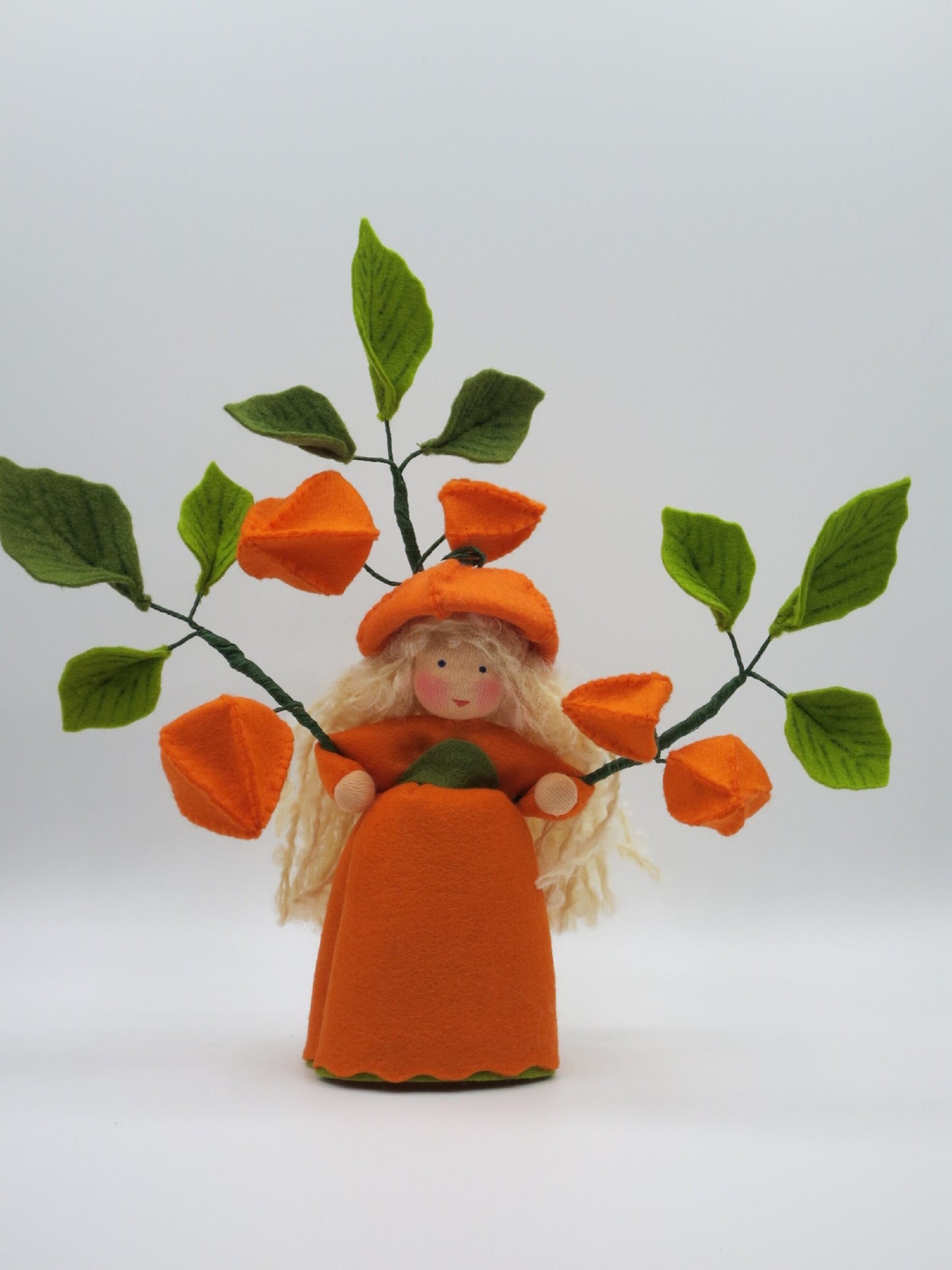 Lampionblume-Mädchen Art. HE49 mit orangem Laternenkleid zwischen Physalis-Zweig, Waldorf-Blumenkind Herbst.