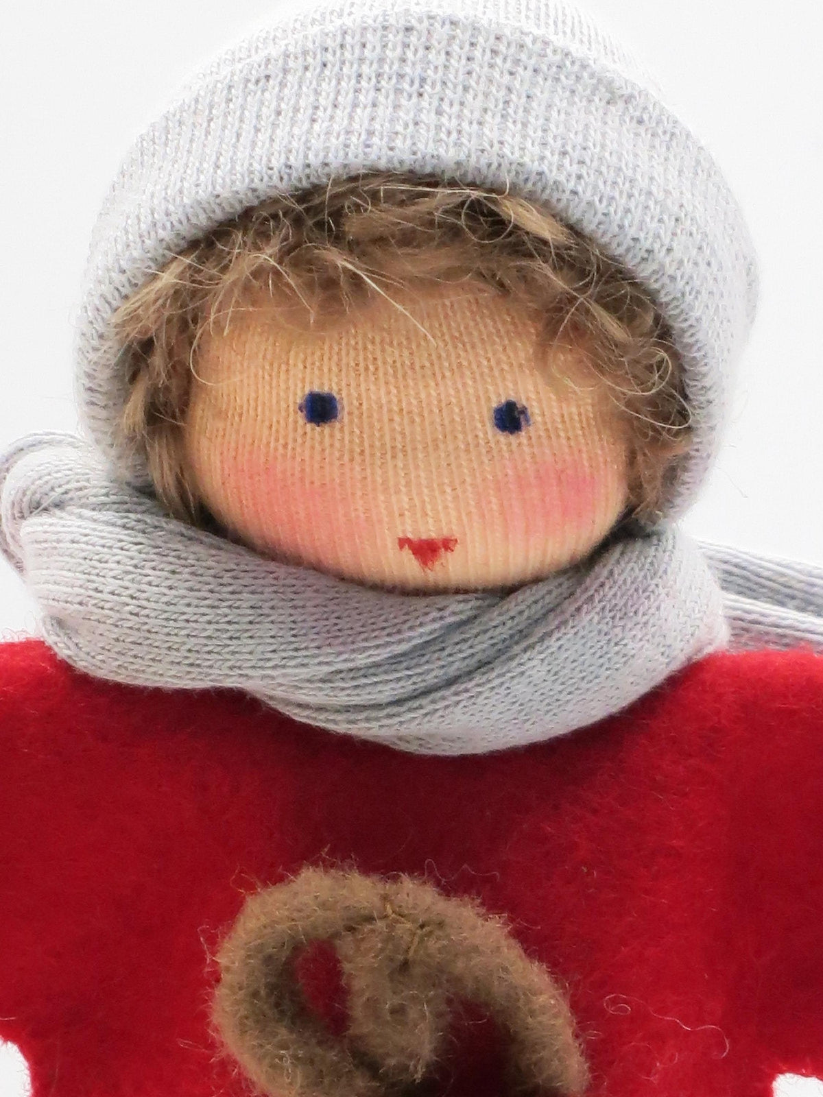 Gesichtsdetail des Laternenkinds in Grau mit gestrickter Mütze, grauem Schal und rotem Wollfilzpullover.