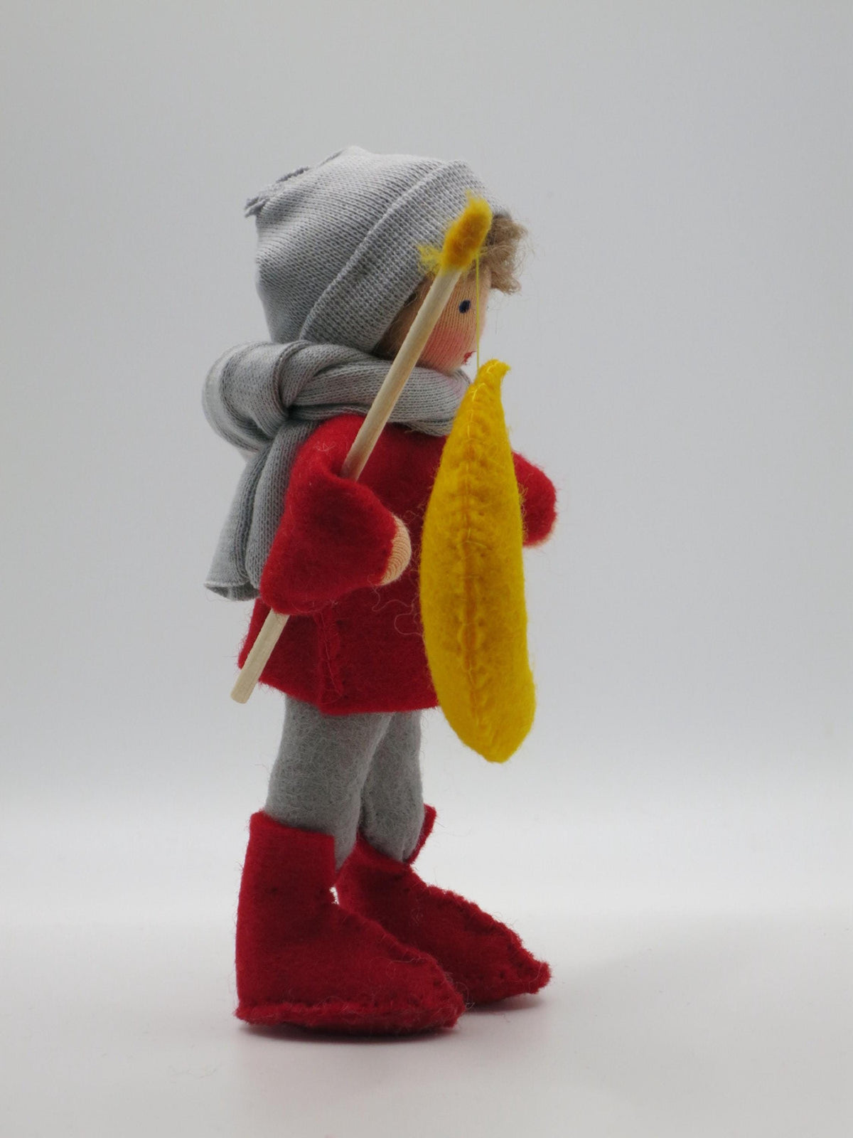 Rückansicht des Laternenkinds in Grau mit rotem Pullover, grauem Schal und Mondlaterne.