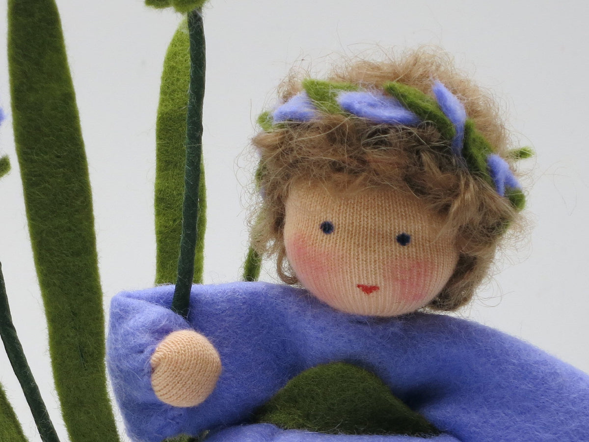 Nahaufnahme des Gesichts der Lavendel-Figur mit violettem Blütenkranz im braunlockigen Haar.