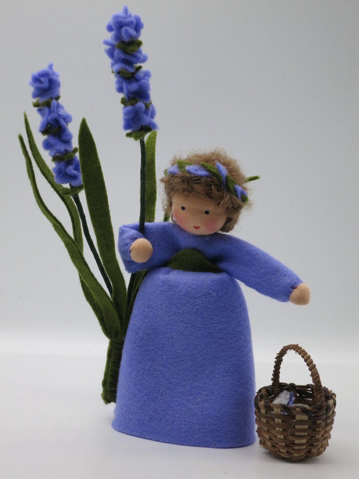 Lavendel-Blumenkind aus Wollfilz für den Waldorf Jahreszeitentisch mit zwei Blütenstielen, Blütenkranz und kleinem Weidenkorb.