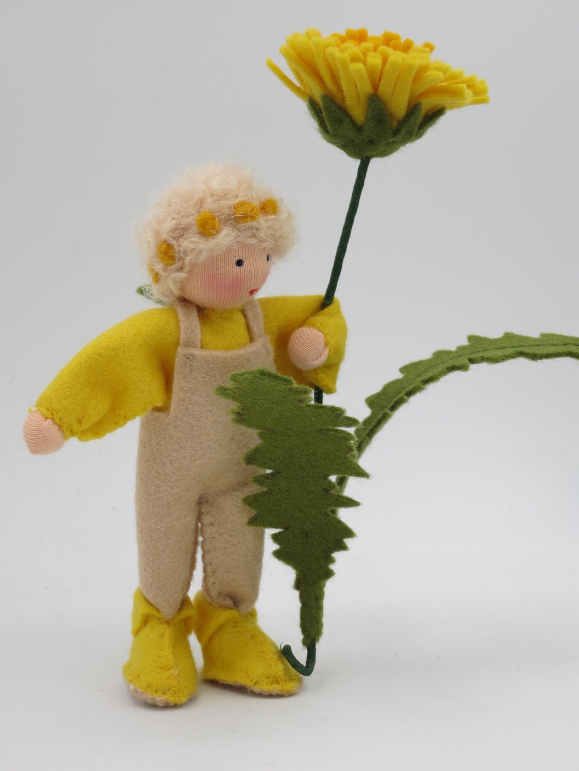 Löwenzahn-Junge Blumenkind hält das gezähnte Löwenzahnblatt in der Hand, Waldorf Jahreszeitentisch