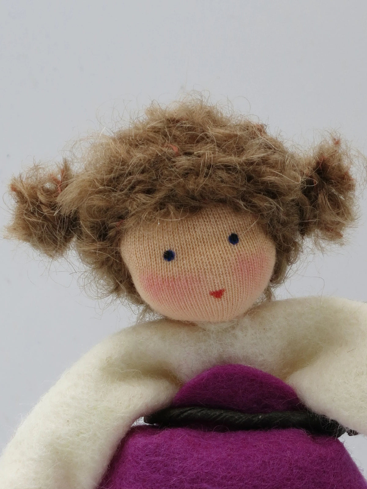 Nahaufnahme des Magnolie-Blumenkind-Gesichts mit braunem Lockenhaar und lila Kleid