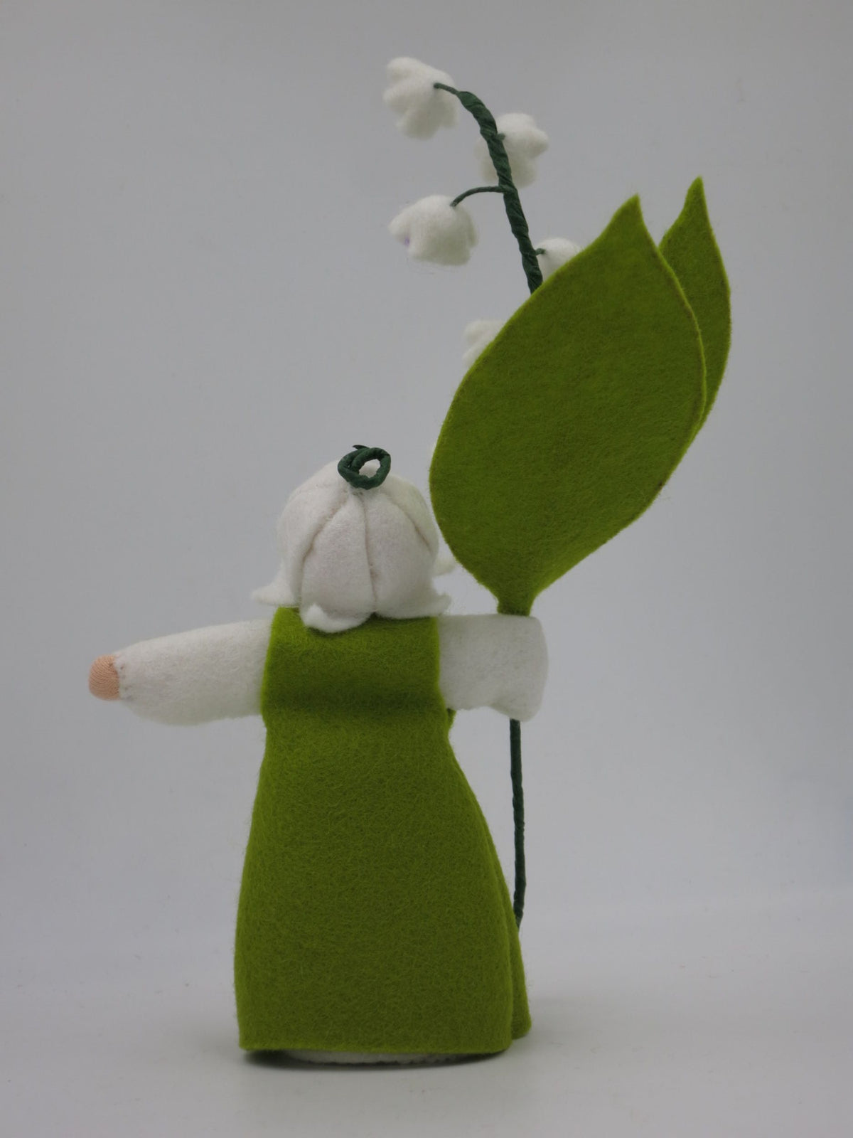 Rückansicht des Maiglöckchen-Blumenkinds mit grünem Filzkleid und Perlenschmuck
