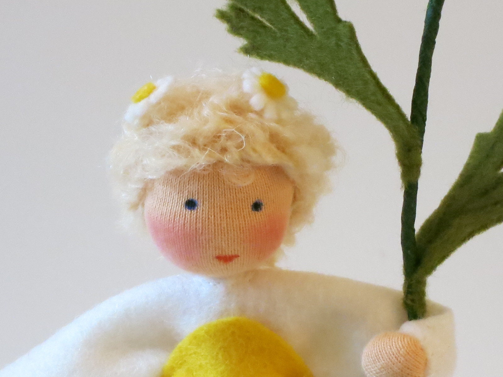 Gesichtsdetail des Margerite-Blumenkindes mit kleinen Filzblüten im Haar, Waldorf-Wollfilzfigur