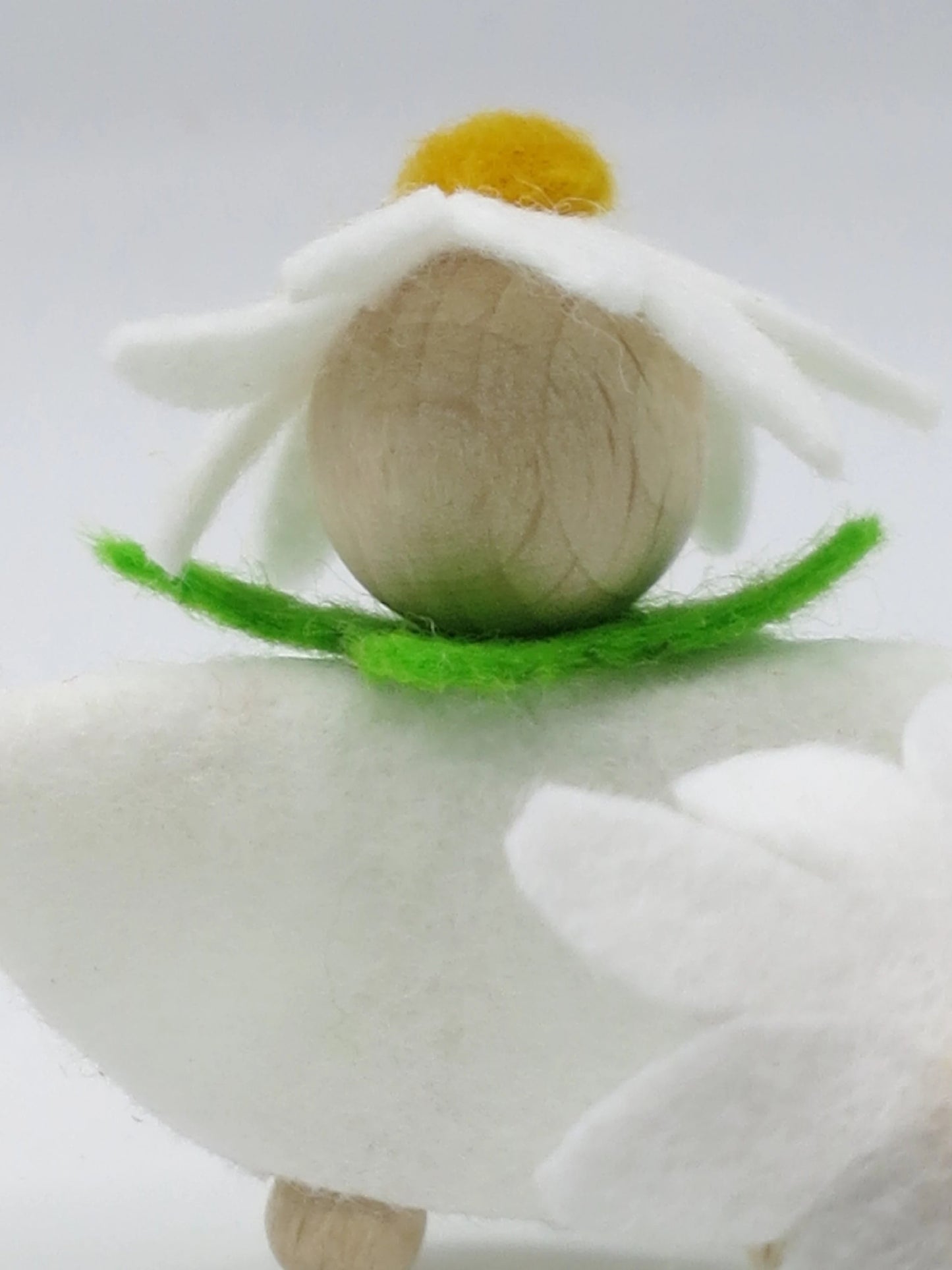 Porträt des Margeriten-Blumenkinds mit naturbelassenem Holzkopf, weißer Blütenhaube und grünem Filzkragen.
