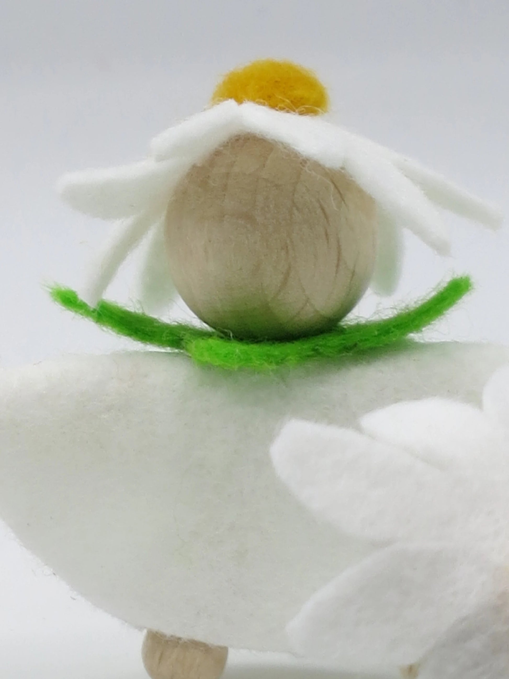 Porträt des Margeriten-Blumenkinds mit naturbelassenem Holzkopf, weißer Blütenhaube und grünem Filzkragen.