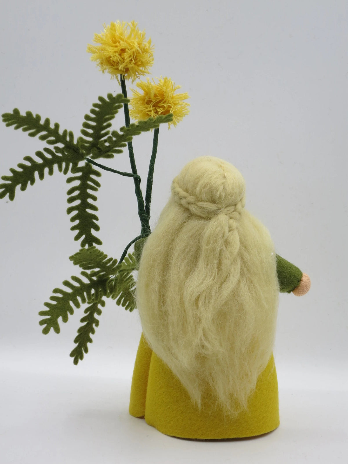 Detailansicht der gelben Mimosen-Pomponblüten aus Wollgarn mit grünem Farnblatt