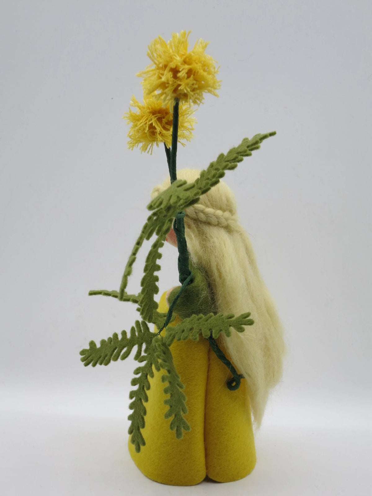 Rückansicht des Mimose-Blumenkinds mit langem blondem Haar und gelben Blütenbällchen