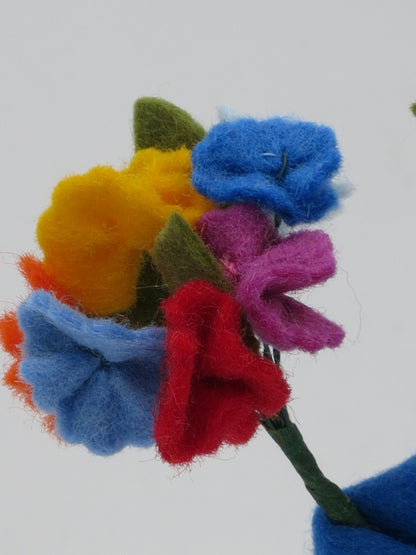 Detailaufnahme des bunten Filz-Blütenstraußes des Mittsommer-Jungen in Gelb, Blau, Orange und Rot.