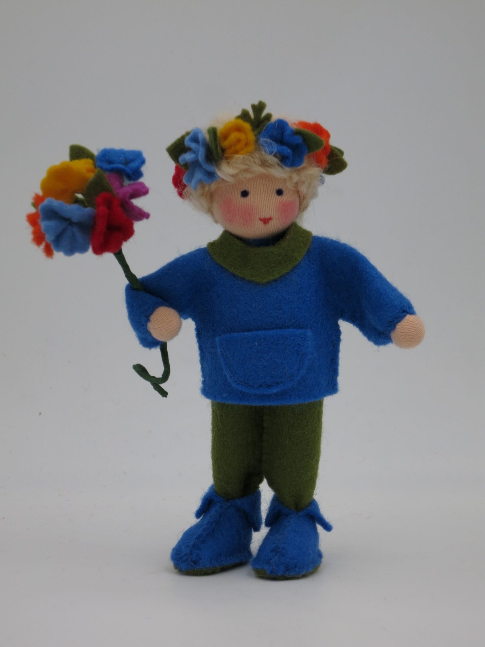 Frontale Nahaufnahme des Mittsommer-Jungen mit buntem Blumenkranz und Blütenstrauß.
