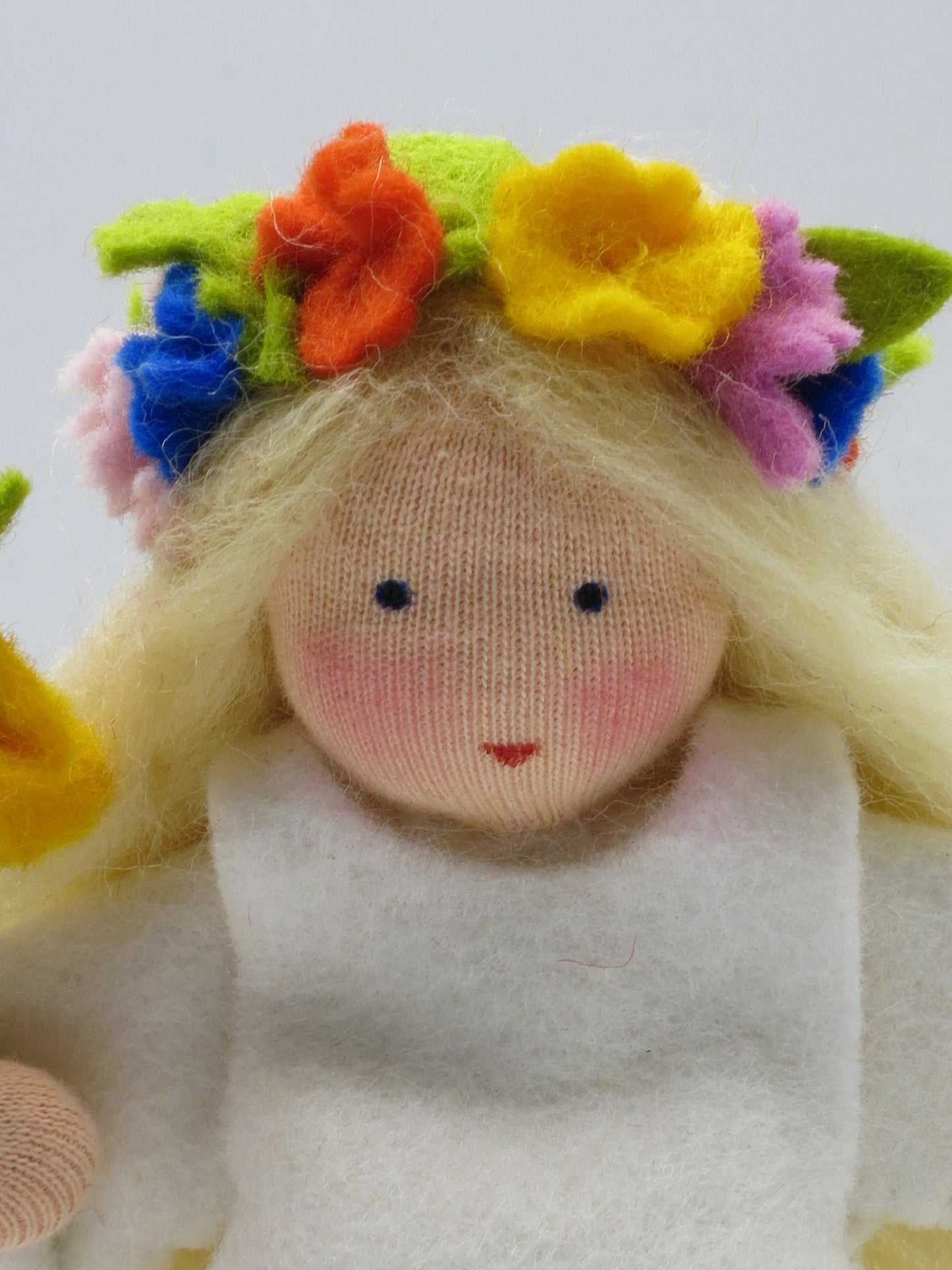 Gesichtsdetail des Mittsommer-Püppchens mit buntem Filz-Blütenkranz, Waldorf-Puppenfigur