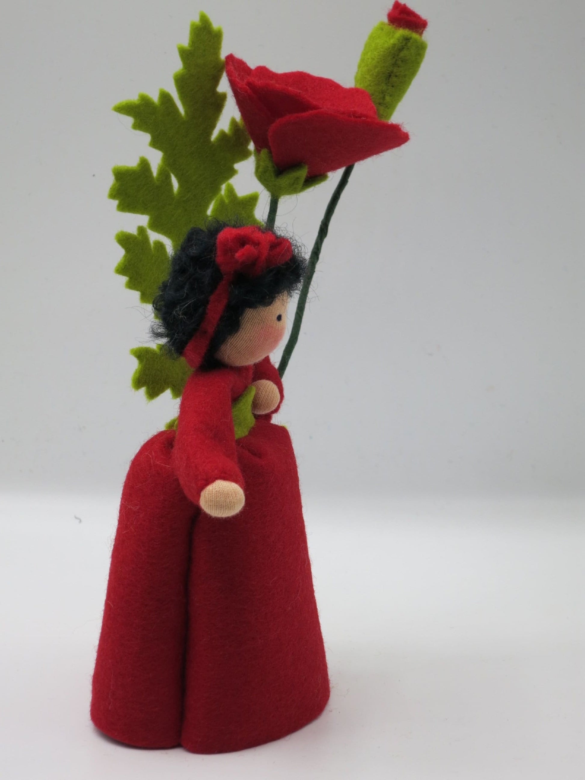 Halbprofil des Mohn-Blumenkinds mit roter Blüte und Knospe am Waldorf-Jahreszeitentisch-Motiv.