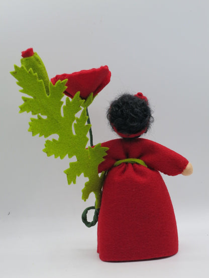 Rückansicht des Mohn-Blumenkinds mit dunklem Haarknoten und roter Schleife, Wollfilz-Handarbeit.