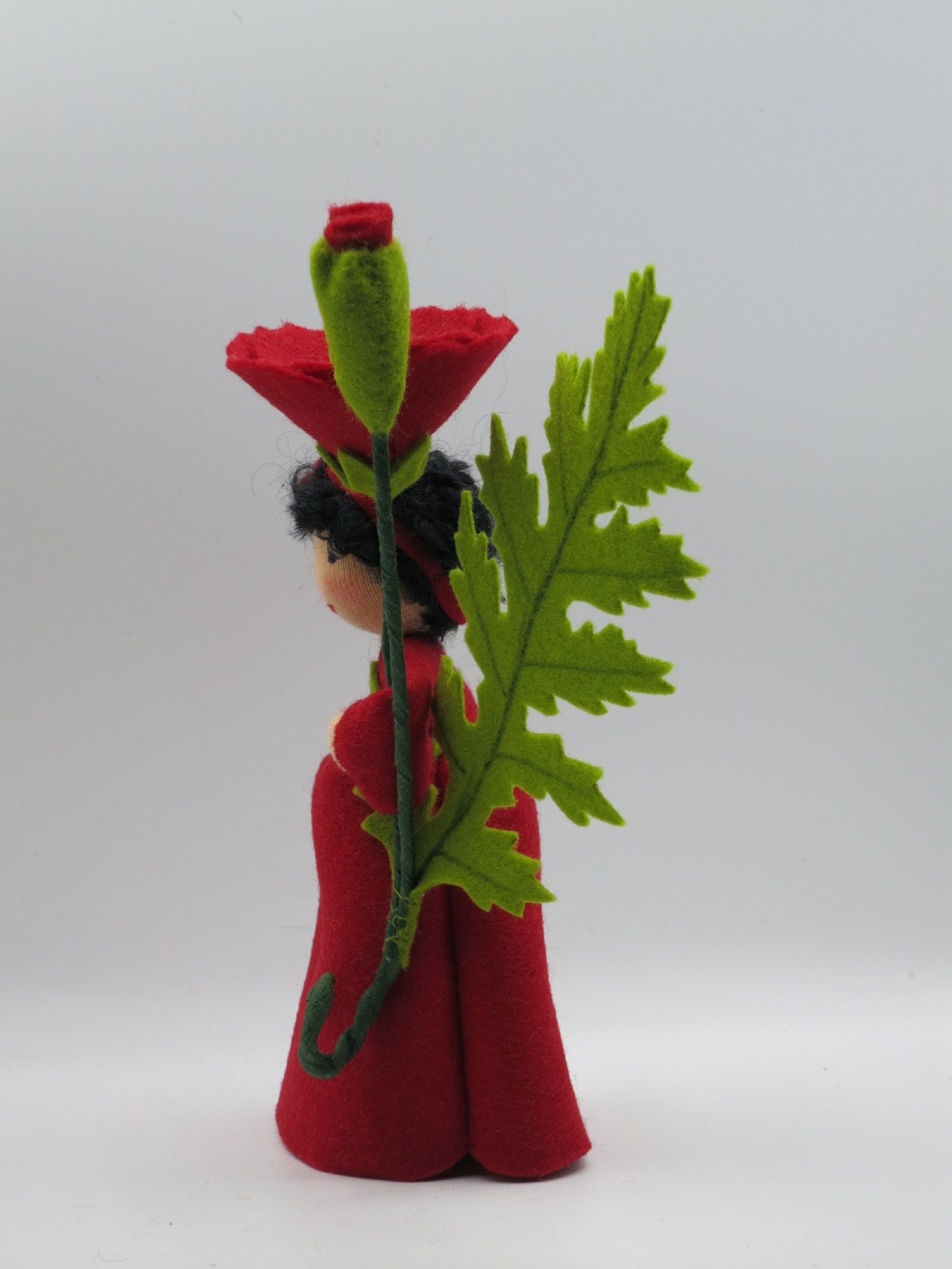 Seitenansicht des Mohn-Blumenkinds mit geschwungener Rankenspirale am Stiel.