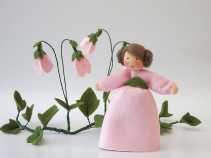 Porträt der Moosglöckchen-Figur mit braunem Zopfkranz und rosa Filzkleid.