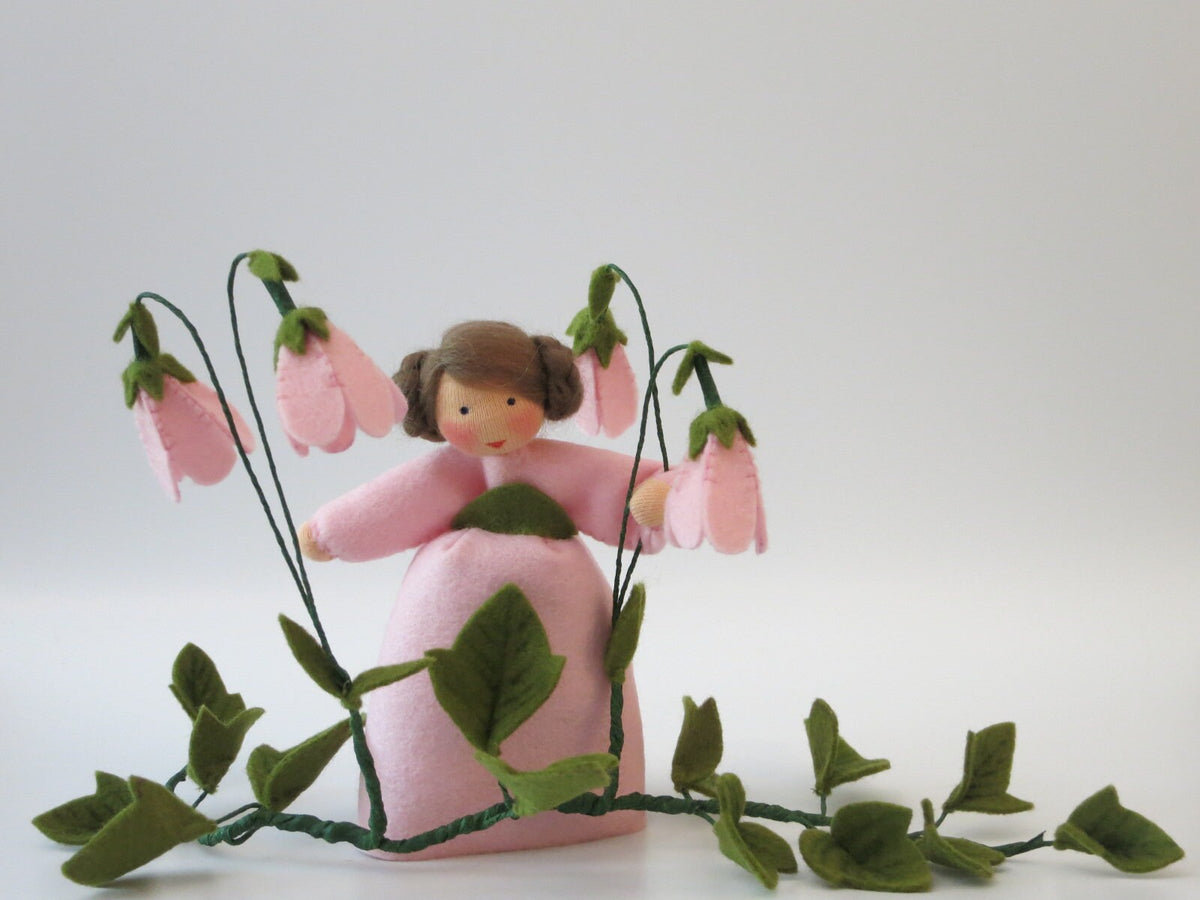 Seitenansicht des Moosglöckchen-Blumenkindes mit rosa Kleid und Blütenzweigen.