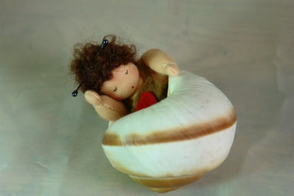 Müdes Schneckchen aus Wollfilz schläft in einem echten Schneckenhaus, Waldorf Jahreszeitentisch.