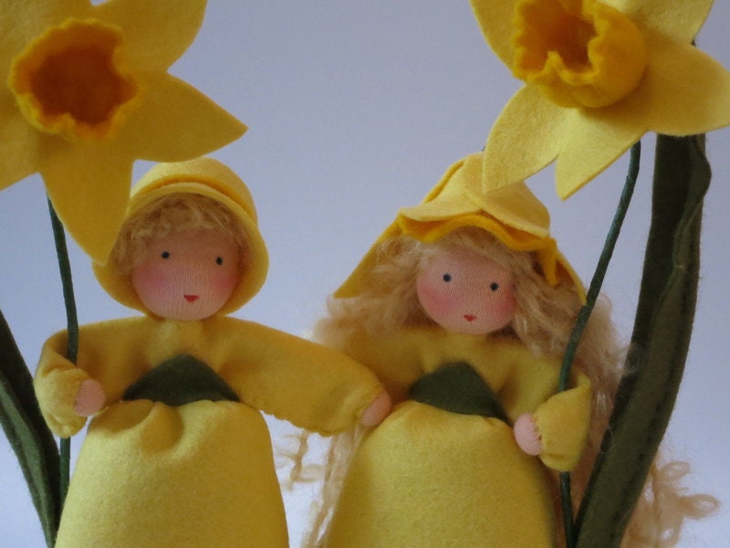Narzissen-Blumenkinder Nahaufnahme mit gelben Trichterblüten, Junge mit Kappe und Mädchen mit Haube