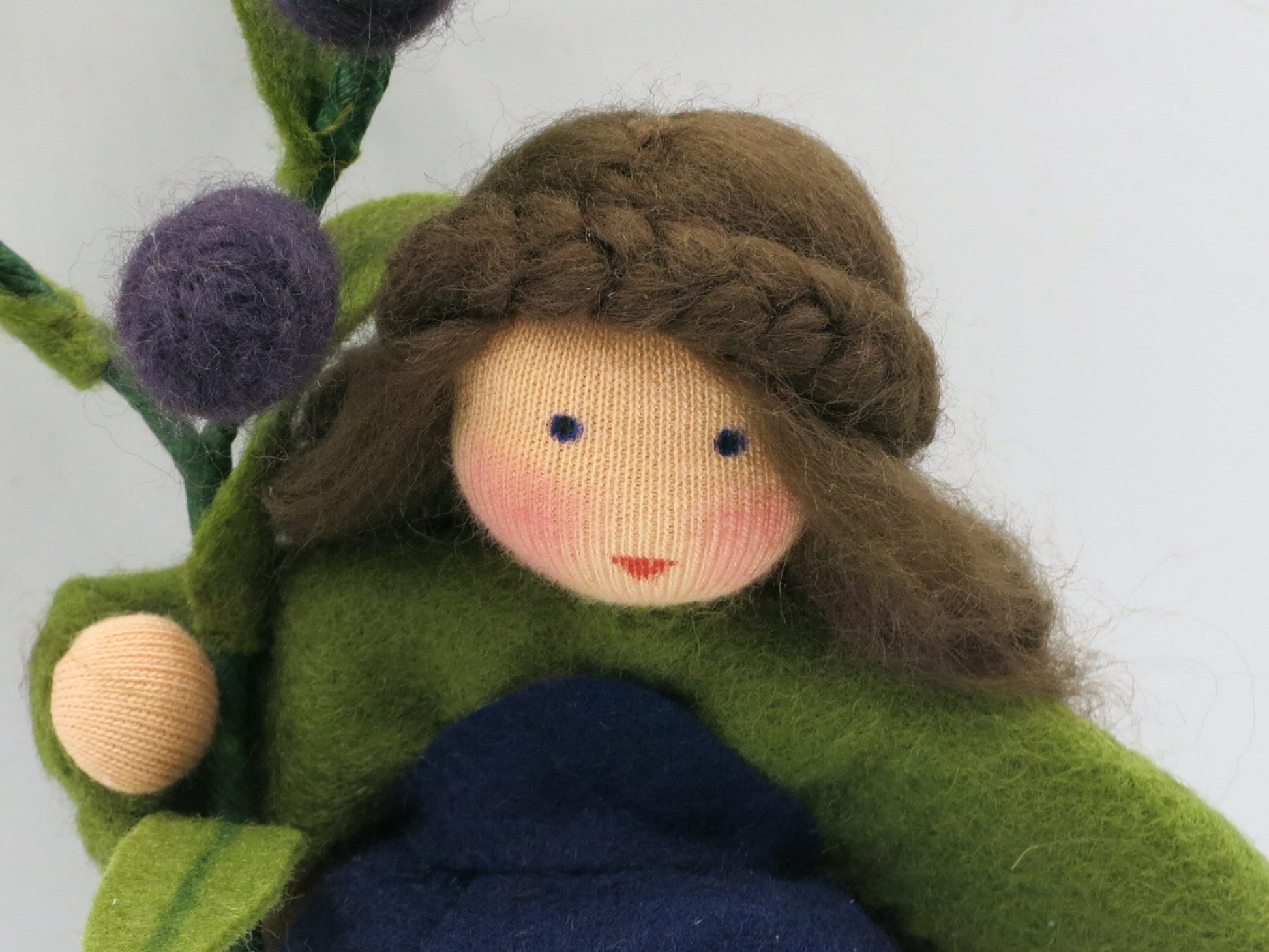 Olive Blumenkind aus Wollfilz, Portraet mit geflochtener Frisur, gruener Bluse und dunkelblauem Rock, Waldorf-Jahreszeitentisch, Art. HE37
