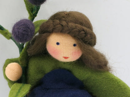 Olive Blumenkind aus Wollfilz, Portraet mit geflochtener Frisur, gruener Bluse und dunkelblauem Rock, Waldorf-Jahreszeitentisch, Art. HE37