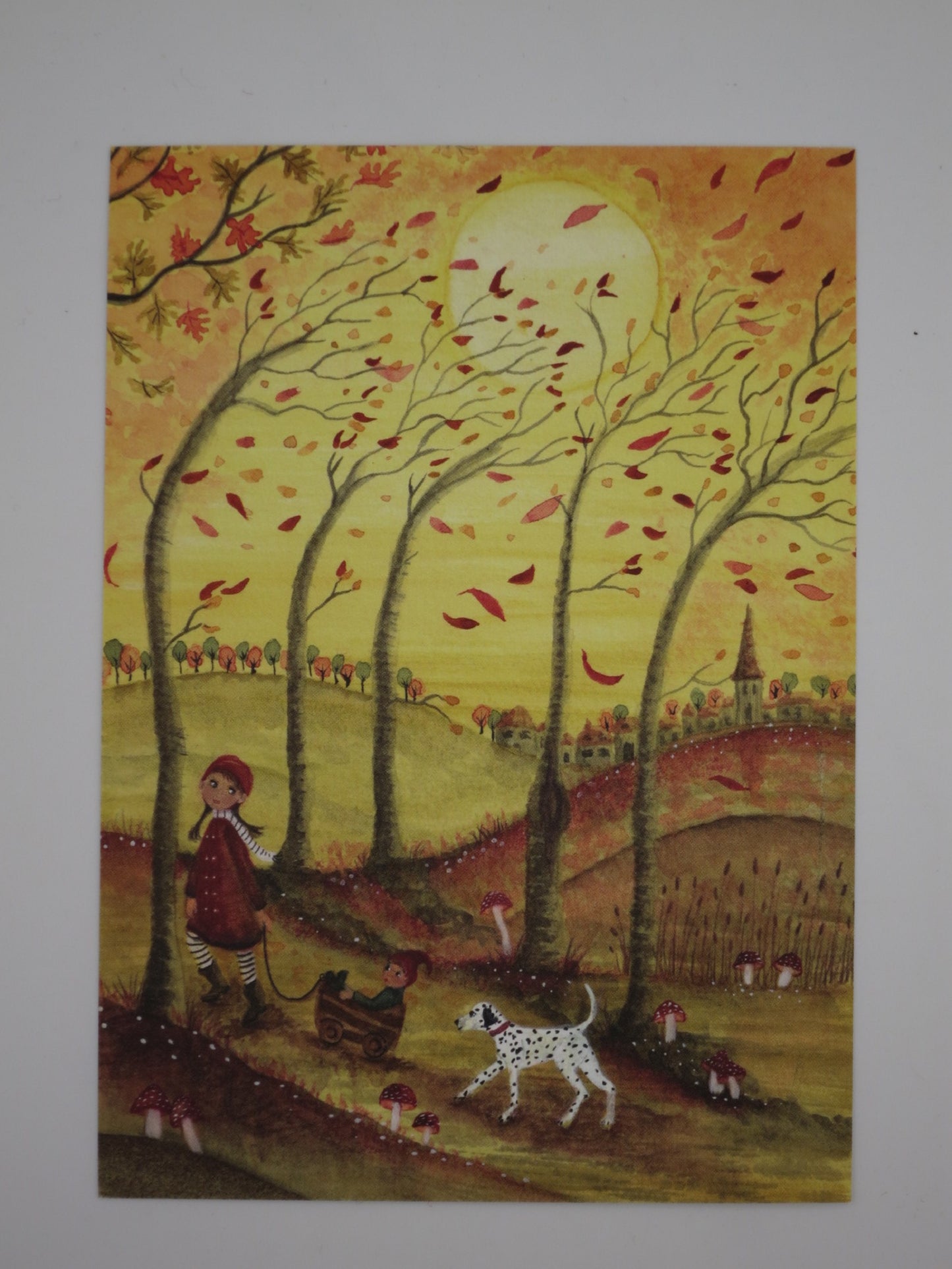 Postkarte Herbstspaß von Bijdehansje: Mädchen zieht Wichtel im Bollerwagen durch windigen Herbsttag