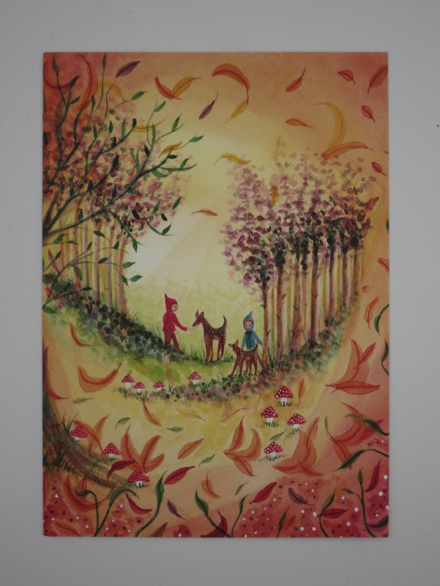 Postkarte Herbst von Bijdehansje: Wichtel mit Reh und Kitz zwischen wirbelnden Herbstblättern