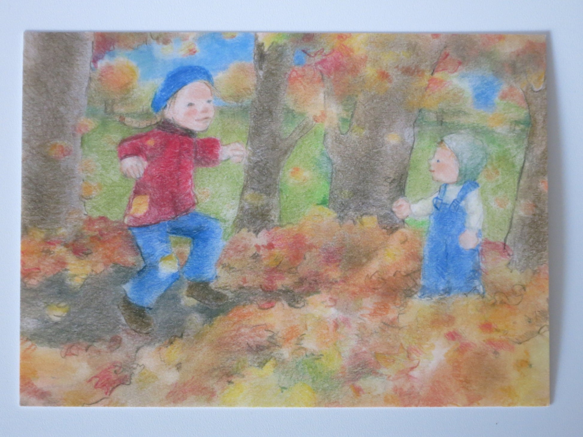 Postkarte Laubhaufen von Sanne Dufft: Kinder spielen am Laubhaufen im Herbstwald