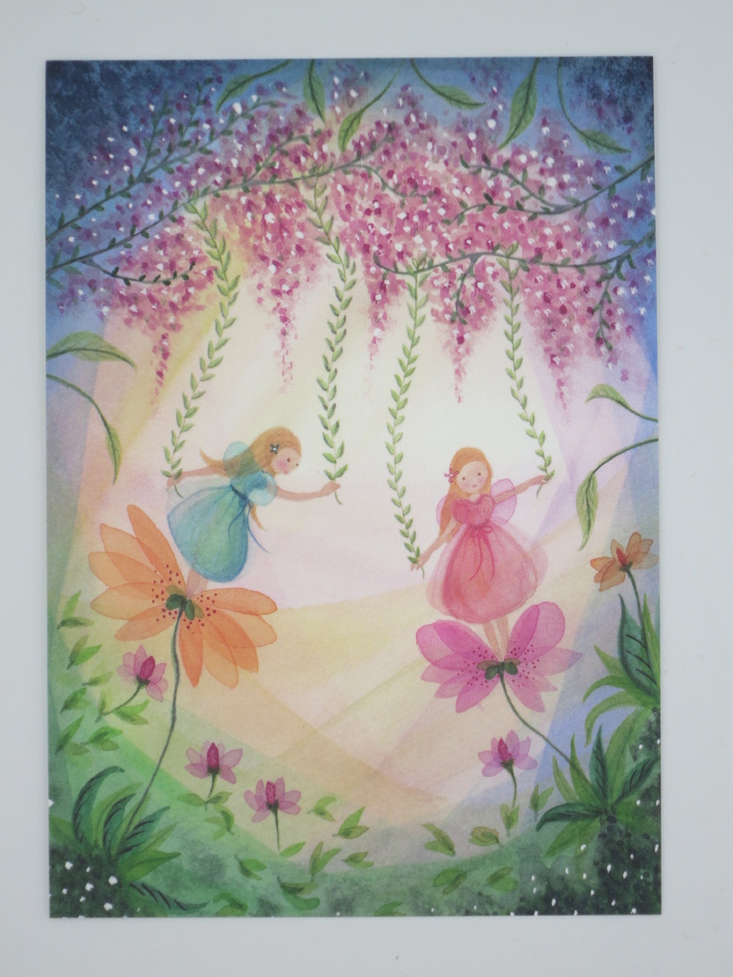 Postkarte Blumenelfen: zwei Elfen schaukeln unter Blauregen-Blüten, Illustration von Bijdehansje